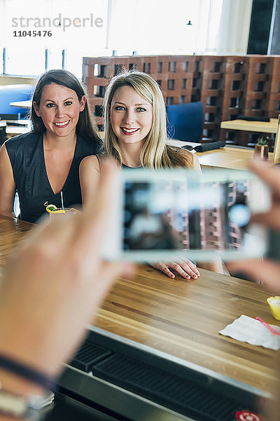 Kaukasischer Barkeeper fotografiert Kunden mit seinem Handy