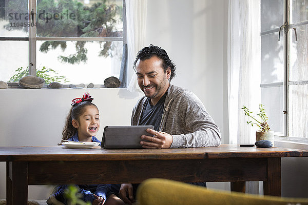 Hispanischer Vater und Tochter benutzen digitales Tablet