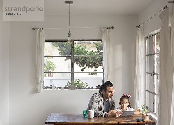 Hispanischer Vater und Tochter benutzen digitales Tablet