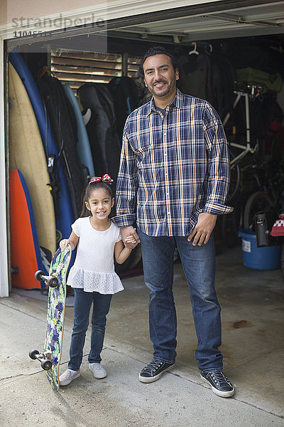 Hispanischer Vater und Tochter lächelnd in der Garage