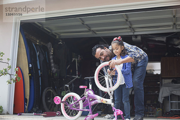 Hispanischer Vater bringt seiner Tochter bei  wie man ein Fahrrad repariert