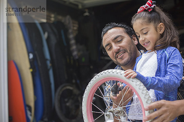 Hispanischer Vater bringt seiner Tochter bei  wie man ein Fahrrad repariert