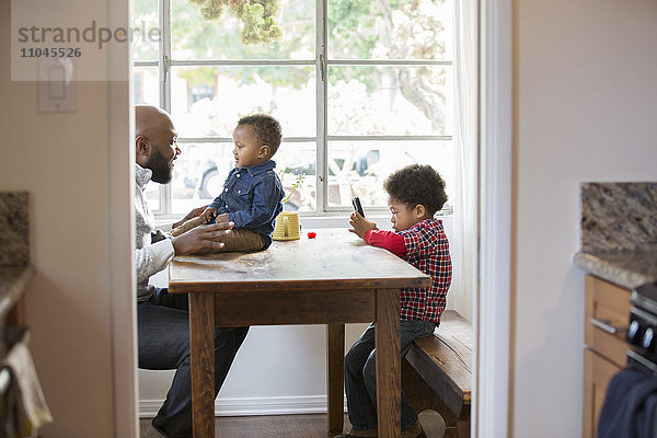 Vater und Kinder sitzen am Tisch