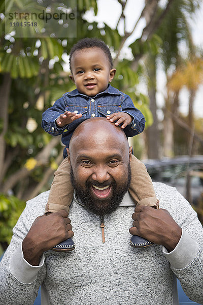 Afroamerikanischer Vater trägt seinen Sohn auf den Schultern