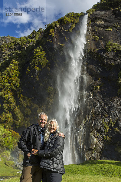 Kaukasisches Paar  das sich in der Nähe eines abgelegenen Wasserfalls umarmt