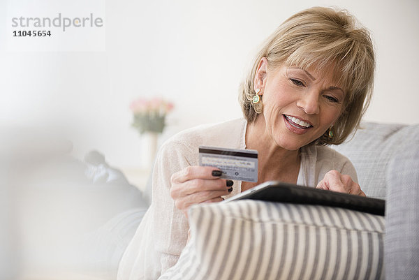 Ältere kaukasische Frau beim Online-Shopping mit digitalem Tablet