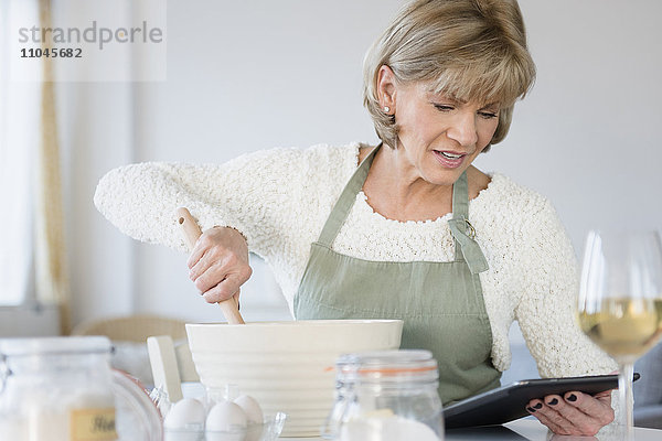 Ältere kaukasische Frau liest Rezept auf digitalem Tablet