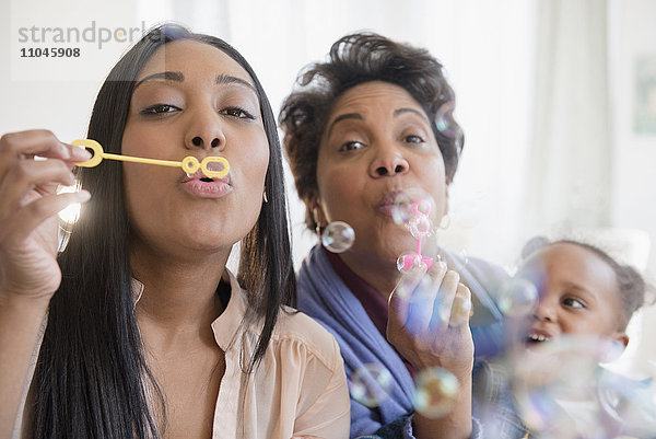 Schwarze Mehrgenerationenfamilie beim Blasen von Seifenblasen mit Seifenblasenstab