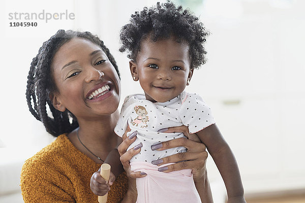 Lächelnde schwarze Mutter hält ihre kleine Tochter