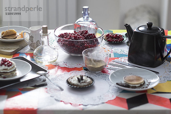 Frühstückstisch mit Tee  Gebäck und Obst auf Spitzendeckchen