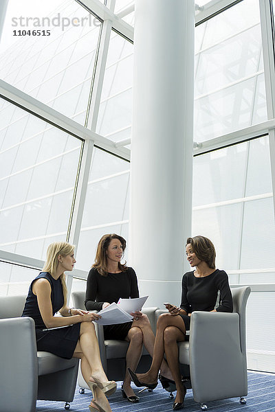 In Sesseln sitzende Geschäftsfrauen im Gespräch