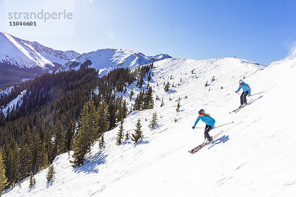 Paar beim Skifahren auf einem verschneiten Berghang