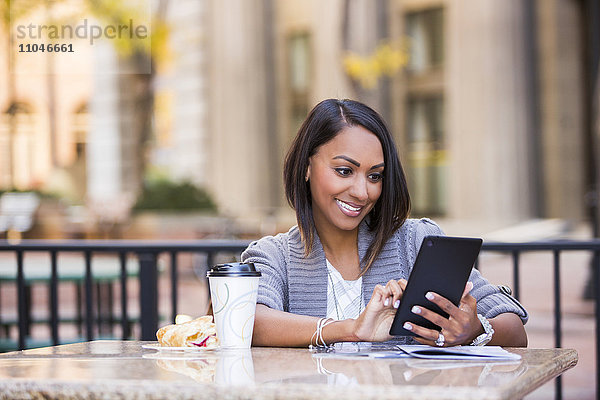 Indische Frau liest in einem Straßencafé auf einem digitalen Tablet