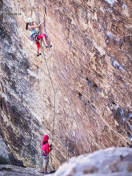 Mutter sichert ihre Tochter beim Klettern am Felsen