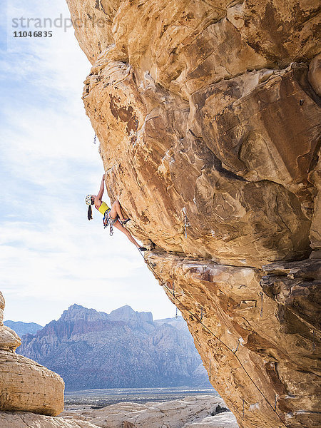 Gemischtrassiges Mädchen beim Klettern am Felsen