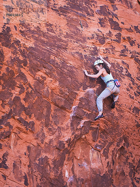 Gemischtrassiges Mädchen beim Klettern am Felsen