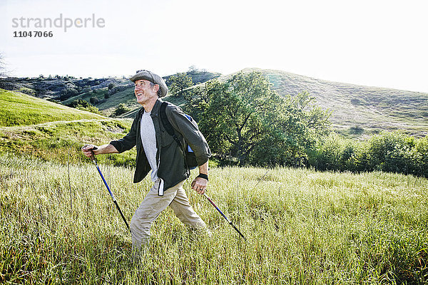 Kaukasischer Mann beim Wandern im Gras auf einem Berg