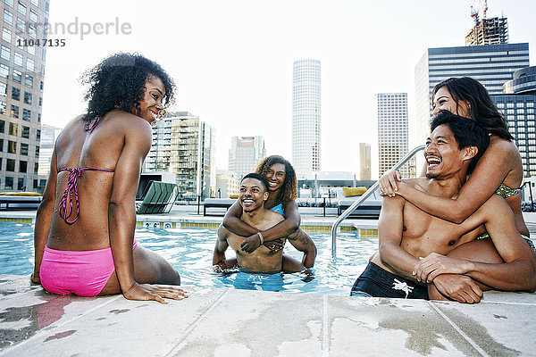 Lächelnde Freunde genießen das städtische Schwimmbad