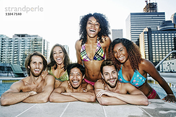 Lächelnde Freunde entspannen sich am Pool eines städtischen Schwimmbads