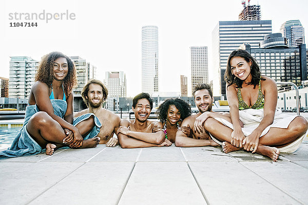 Lächelnde Freunde entspannen sich am Pool eines städtischen Schwimmbads