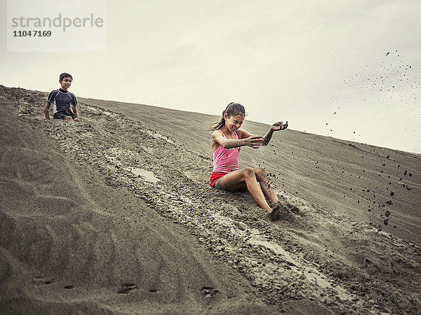 Kinder rutschen auf einer Sanddüne