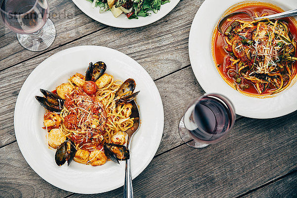 Teller mit Meeresfrüchten und Pasta mit Weingläsern