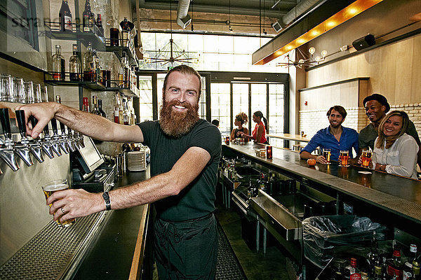 Lächelnder Barkeeper schenkt Bier an der Bar ein