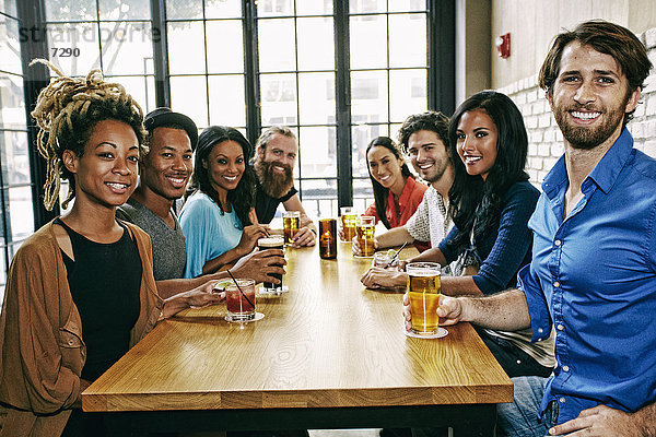 Lächelnde Freunde posieren am Tisch in einer Bar