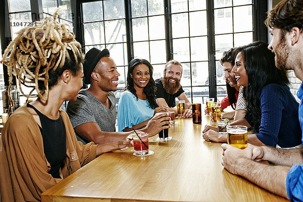 Lächelnde Freunde trinken am Tisch in einer Bar