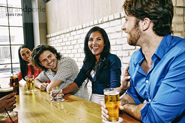 Lächelnde Freunde trinken am Tisch in einer Bar