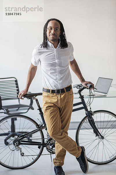 Schwarzer Geschäftsmann mit Fahrrad im Büro