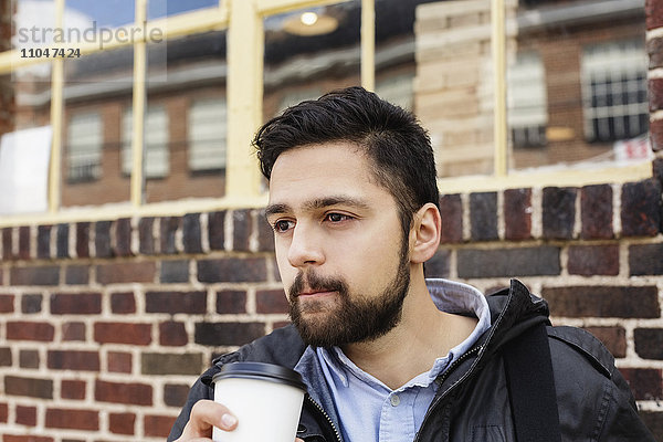 Hispanischer Mann mit Tasche trinkt Kaffee in der Stadt