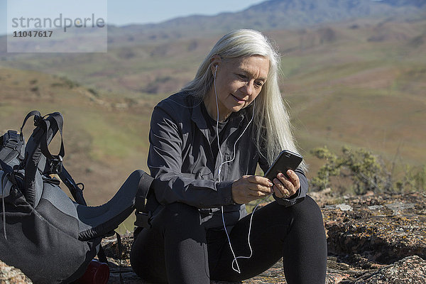 Ältere kaukasische Frau  die auf einem Berg mit ihrem Handy telefoniert