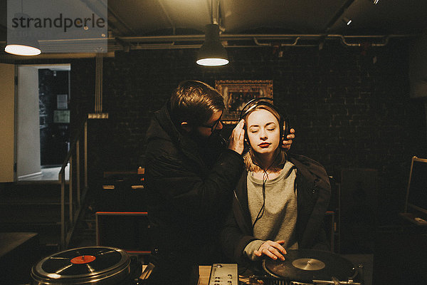 Kaukasischer DJ hält Kopfhörer auf Frau
