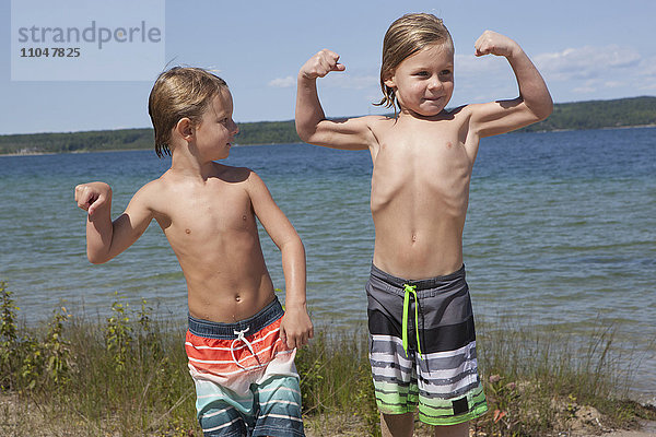 Kaukasische Jungen beim Muskeltraining am Strand