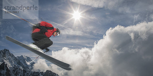 Kaukasischer Skifahrer  der auf einem Berg in die Luft springt