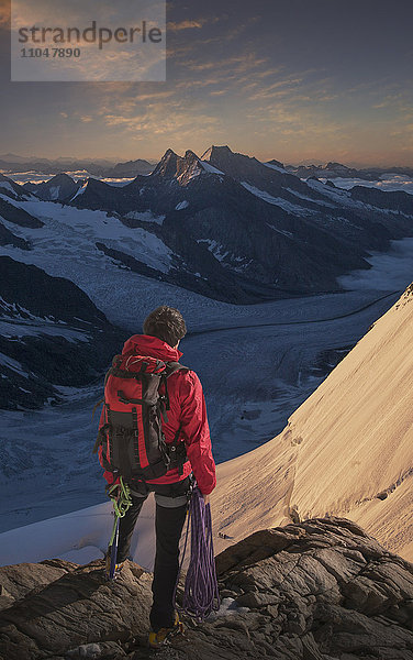 Kaukasischer Mann bewundert Bergkette und hält Kletterseil
