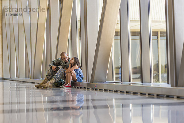 Heimkehrender Soldat im Gespräch mit seiner Tochter am Flughafen