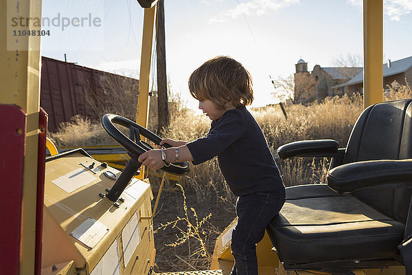 Kaukasischer Junge im Vorschulalter fährt Traktor