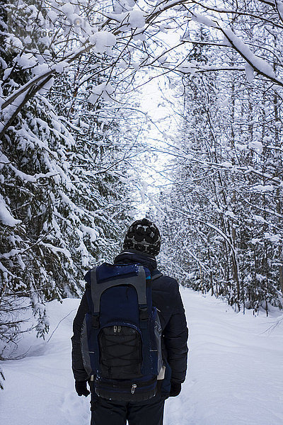 Kaukasischer Wanderer im verschneiten Wald stehend