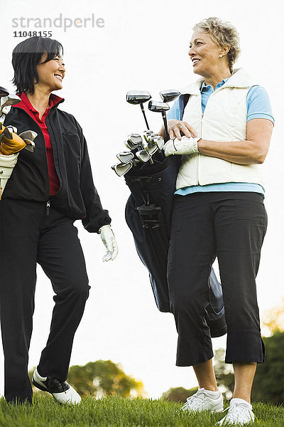 Frauen tragen Golfschläger auf dem Golfplatz