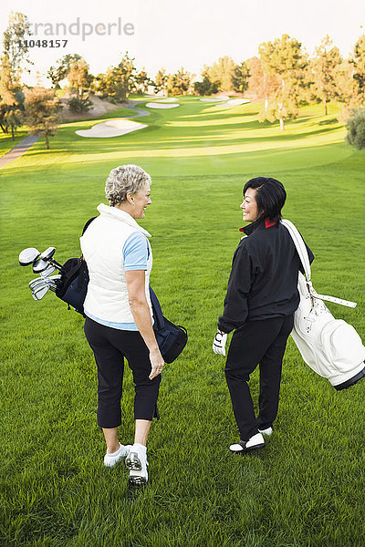 Frauen tragen Golfschläger auf dem Golfplatz