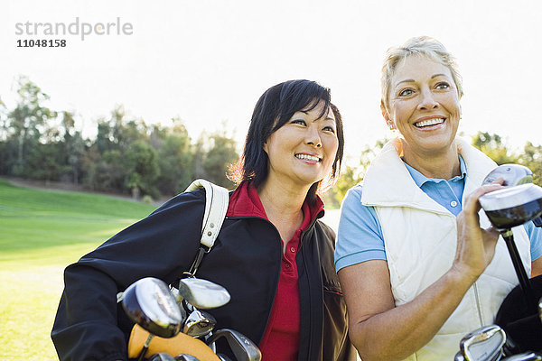 Frauen tragen Golfschläger auf dem Golfplatz