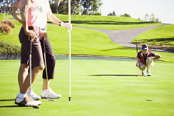 Frauen planen Putt auf dem Grün des Golfplatzes