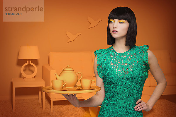 Kaukasische Frau in orangefarbenem  altmodischem Wohnzimmer mit Teeservice