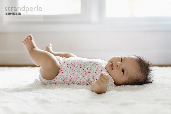 Gemischte Rasse Baby Mädchen auf dem Boden liegend