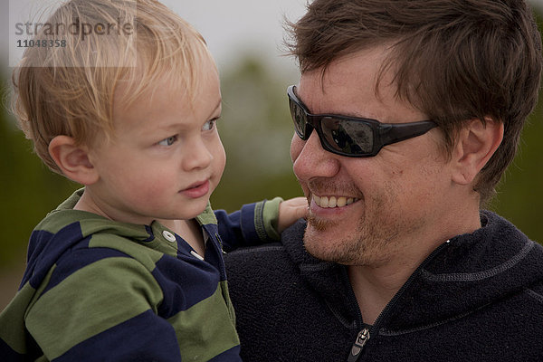 Kaukasischer Vater mit Sonnenbrille hält seinen Sohn