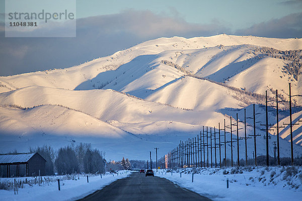 Verschneite Berge über der Straße in abgelegener Landschaft