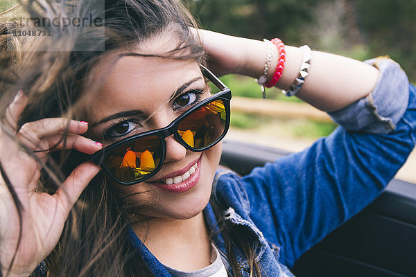 Hispanische Frau  die über eine Sonnenbrille blickt