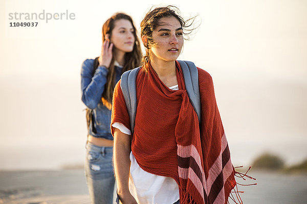 Gemischtrassige Frauen gehen am Strand spazieren